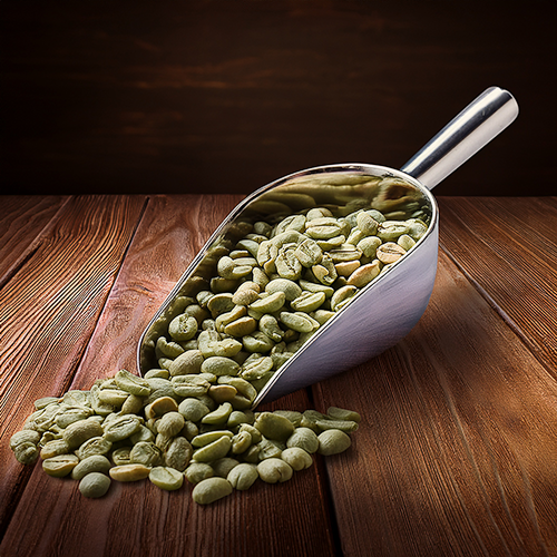 Green coffee beans in a scoop on a wooden table